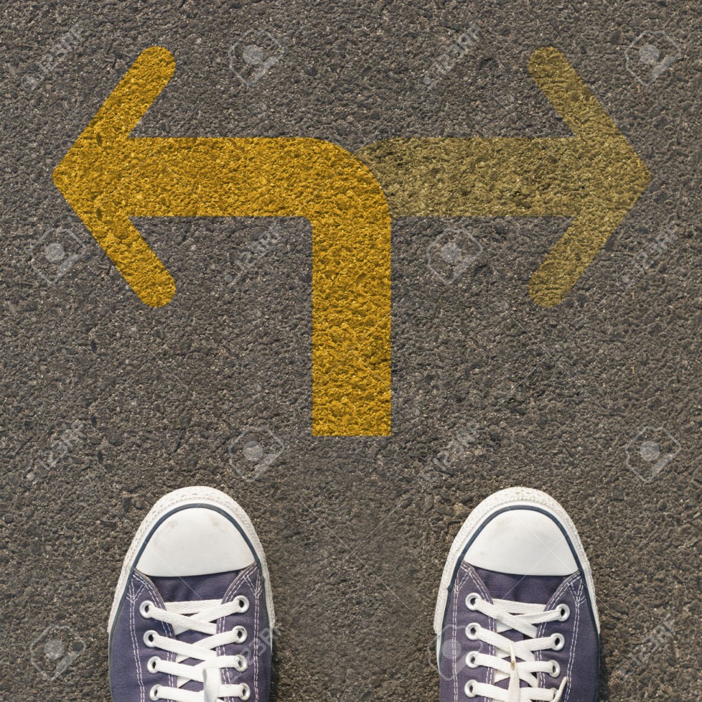 Pair of shoes standing on a road with two way yellow arrow